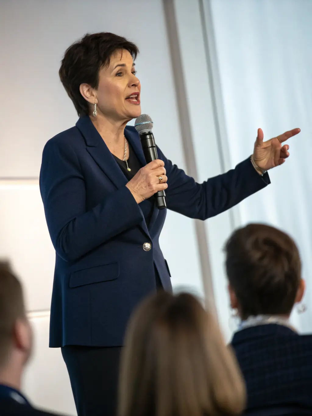 A person confidently speaking into a microphone at a workshop, sharing their story with an attentive audience, representing the empowerment that comes from voicing experiences of workplace bullying.